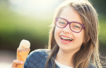 laughing girl with orthodontic braces holding an ice cream