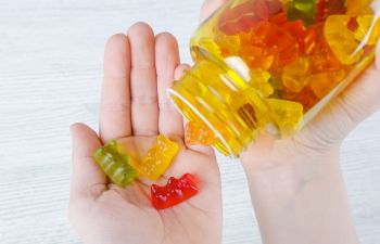 Child taking vitamin jelly candies from a jar.