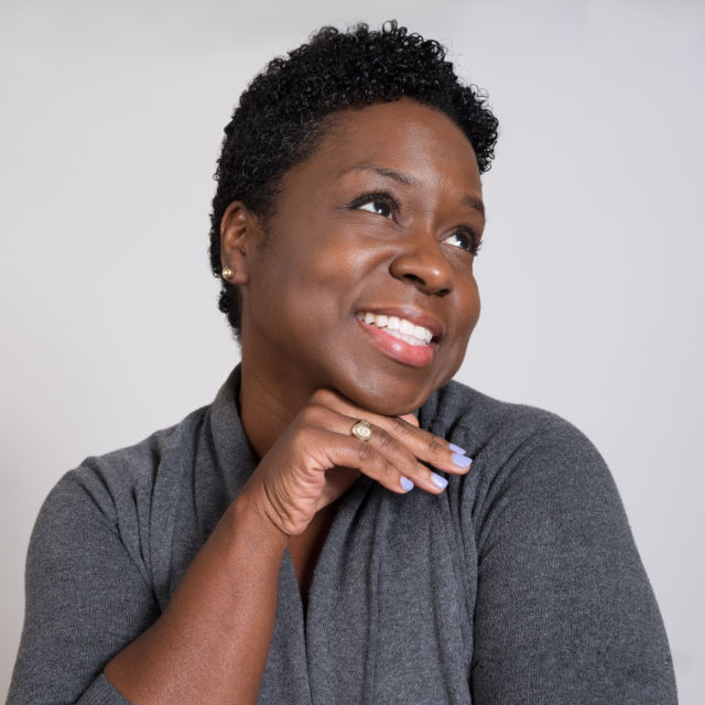 Person gazes upward with a smile, resting chin on hand.