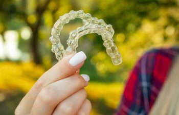 A woman's hand holding a set of clear orthodontic aligners
