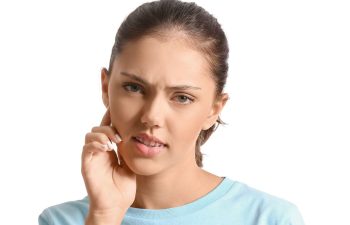 An upset teenage girl wearing dental braces with gum pain